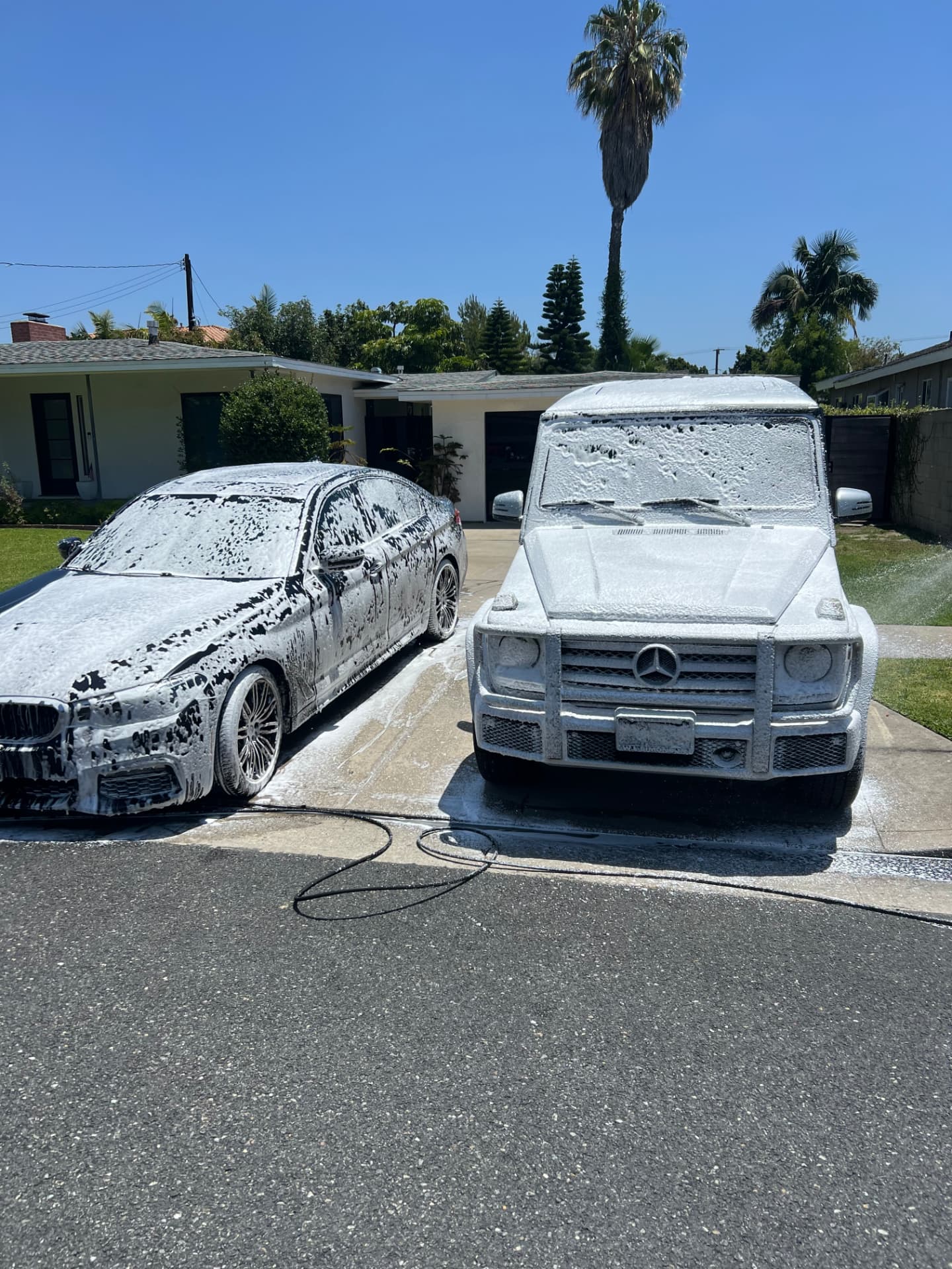 Two cars covered in thick foam during a mobile exterior wash in Downey, CA